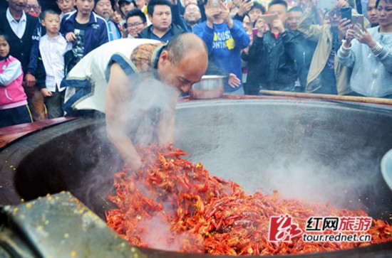 “鬼谷神功”大师唐程刚将手伸进油锅，翻炒龙虾。